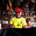 Homem idoso e menino criam uma obra de arte juntos em uma oficina colorida.