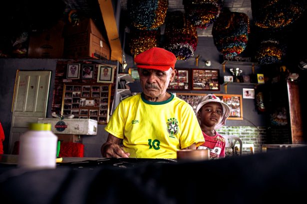 Homem idoso e menino criam uma obra de arte juntos em uma oficina colorida.