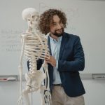 Professor apresenta um modelo de esqueleto a uma turma em sala de aula.