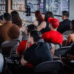 Público diverso acompanha atentamente um seminário em ambiente interno.