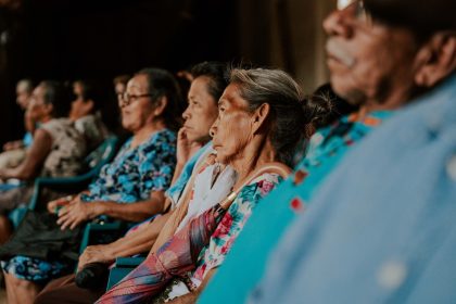 Pessoas idosas sentadas em um auditório, acompanhando atentamente uma atividade ou palestra