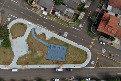 Vista aérea de uma interseção de ruas e avenidas ao lado de uma área verde.
