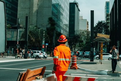Trabalhador da construção em meio ao movimento urbano de São Paulo.