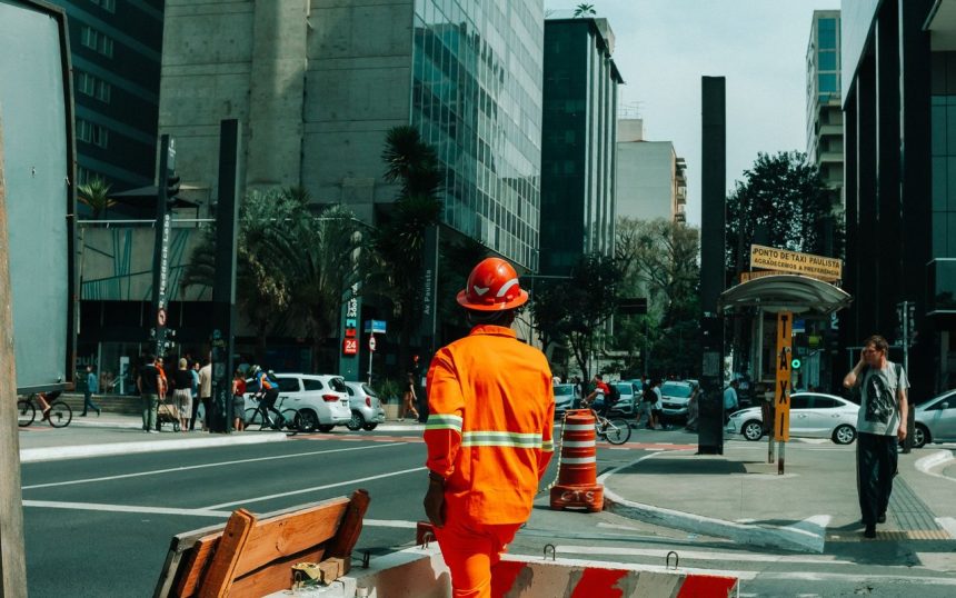 Trabalhador da construção em meio ao movimento urbano de São Paulo.