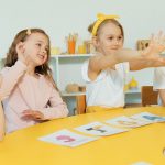 Crianças do ensino fundamental participam de uma atividade de alfabetização com cartões de letras em uma sala de aula.