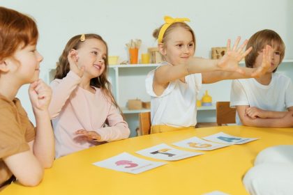 Crianças do ensino fundamental participam de uma atividade de alfabetização com cartões de letras em uma sala de aula.