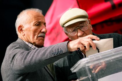 Dois eleitores idosos depositam seus votos em uma seção eleitoral.